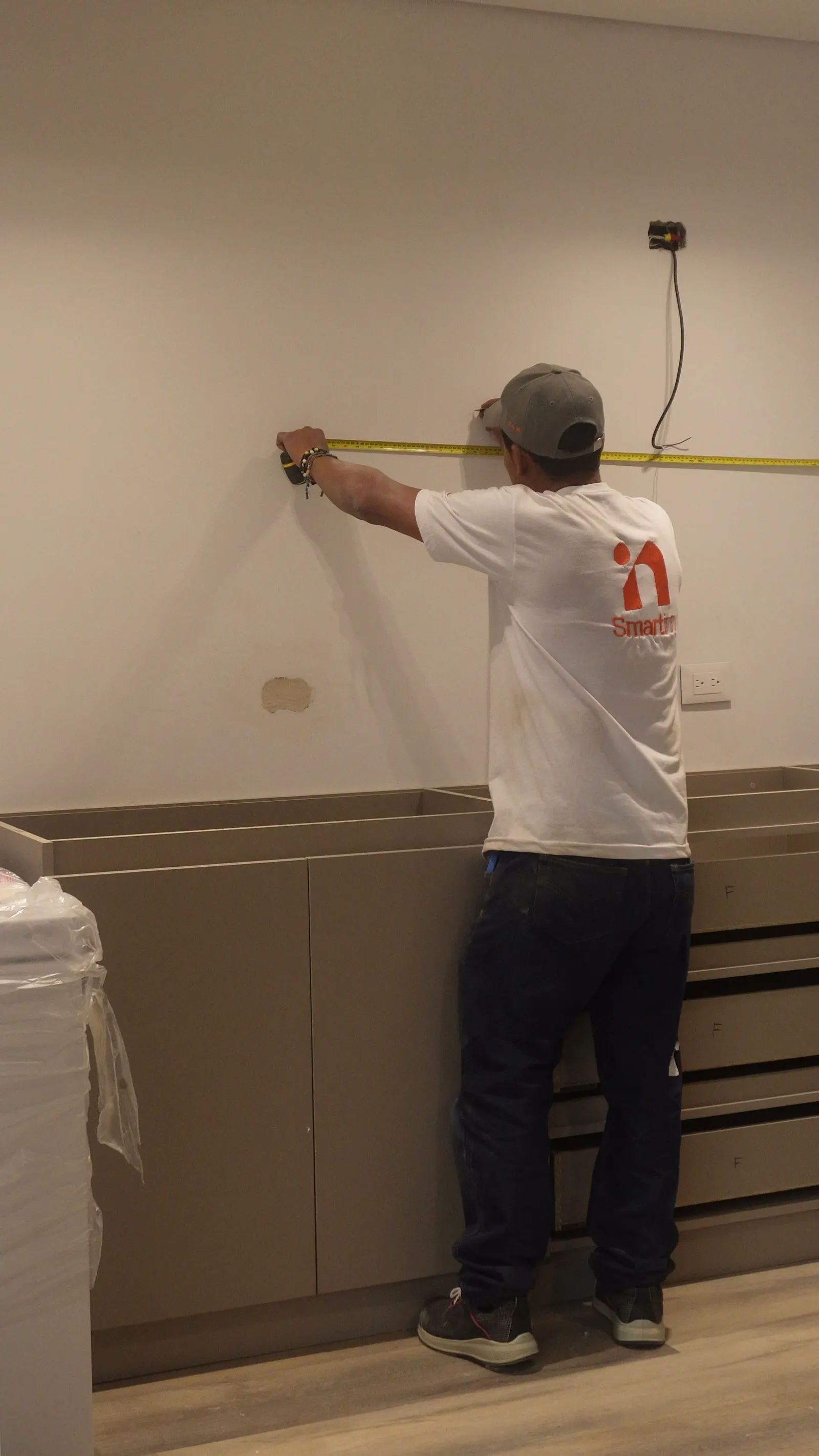 Integrante de Smartinn midiendo en obra la pared donde irá un mueble a medida, primer paso de la remodelación