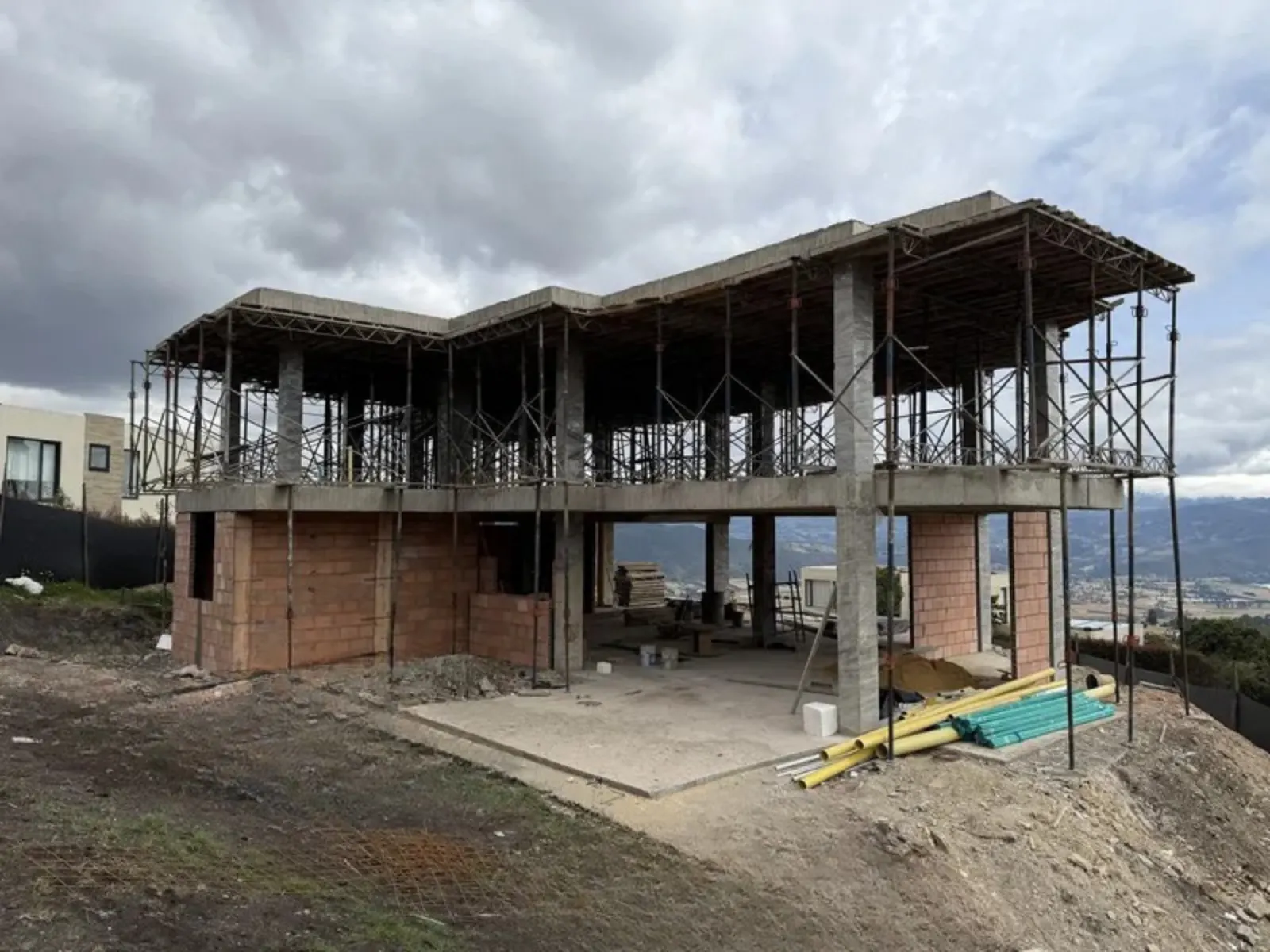 Casa de dos pisos en obra gris, con estructura de concreto y andamios
