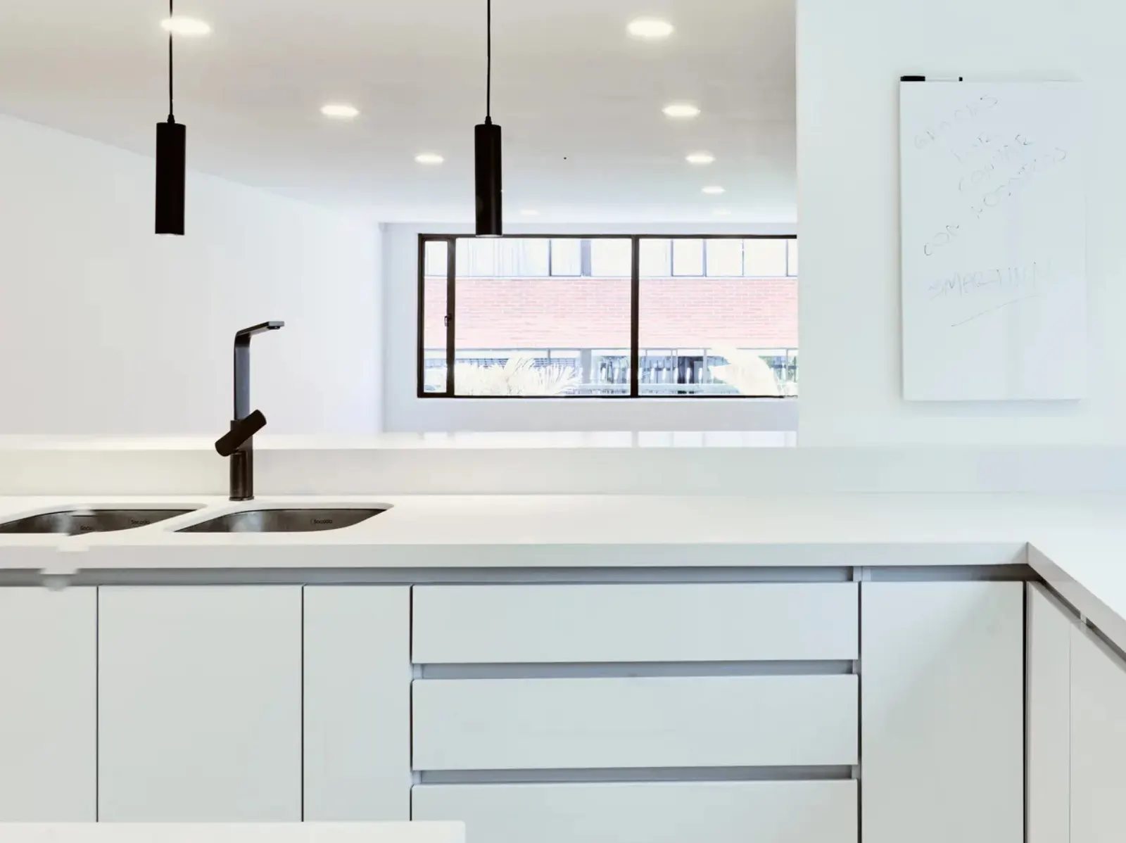 Cocina remodelada con muebles blancos a medida, mesón en L y lámparas colgantes