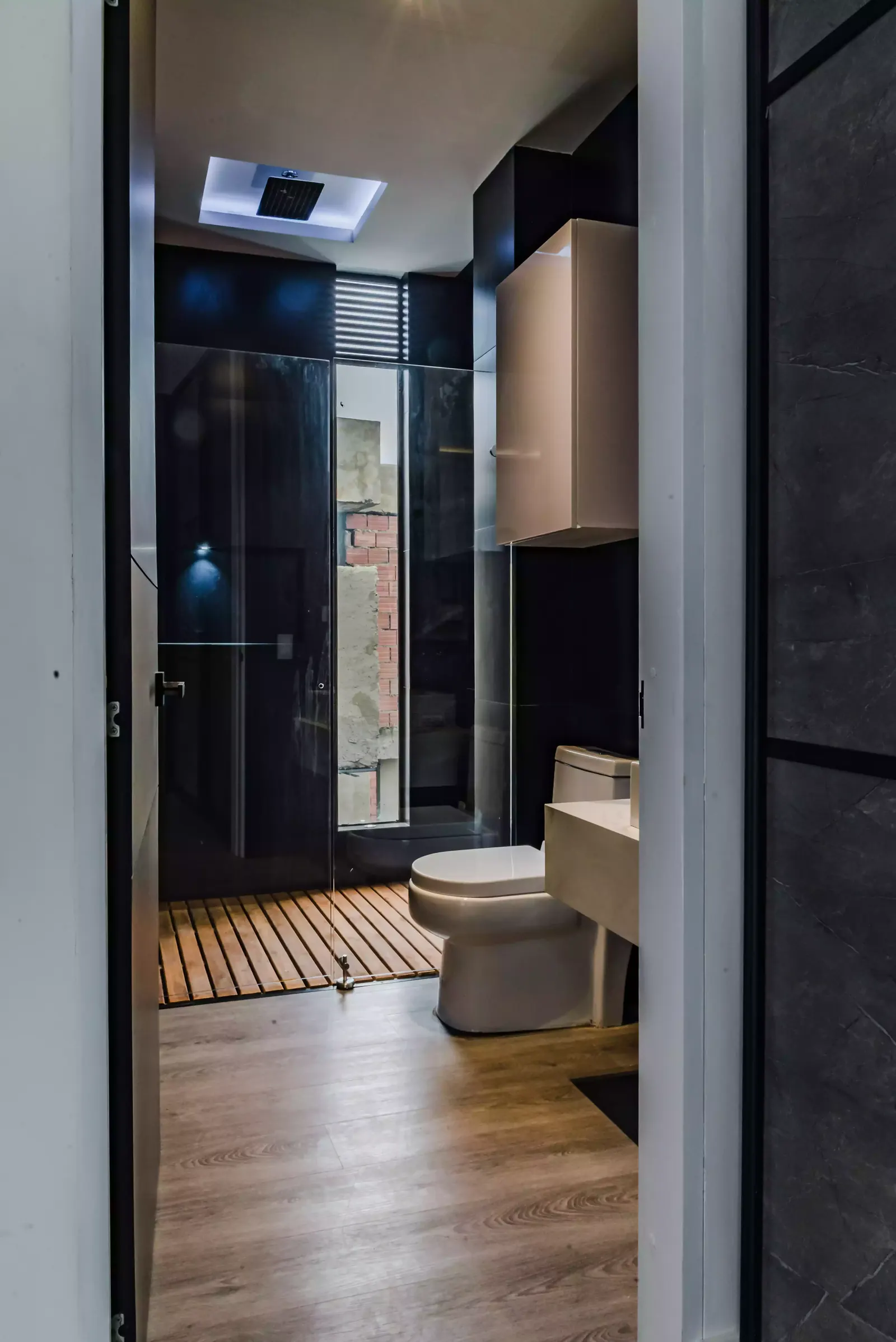 Mueble de lavamanos flotante fabricado a medida y ducha en vidrio con piso de madera