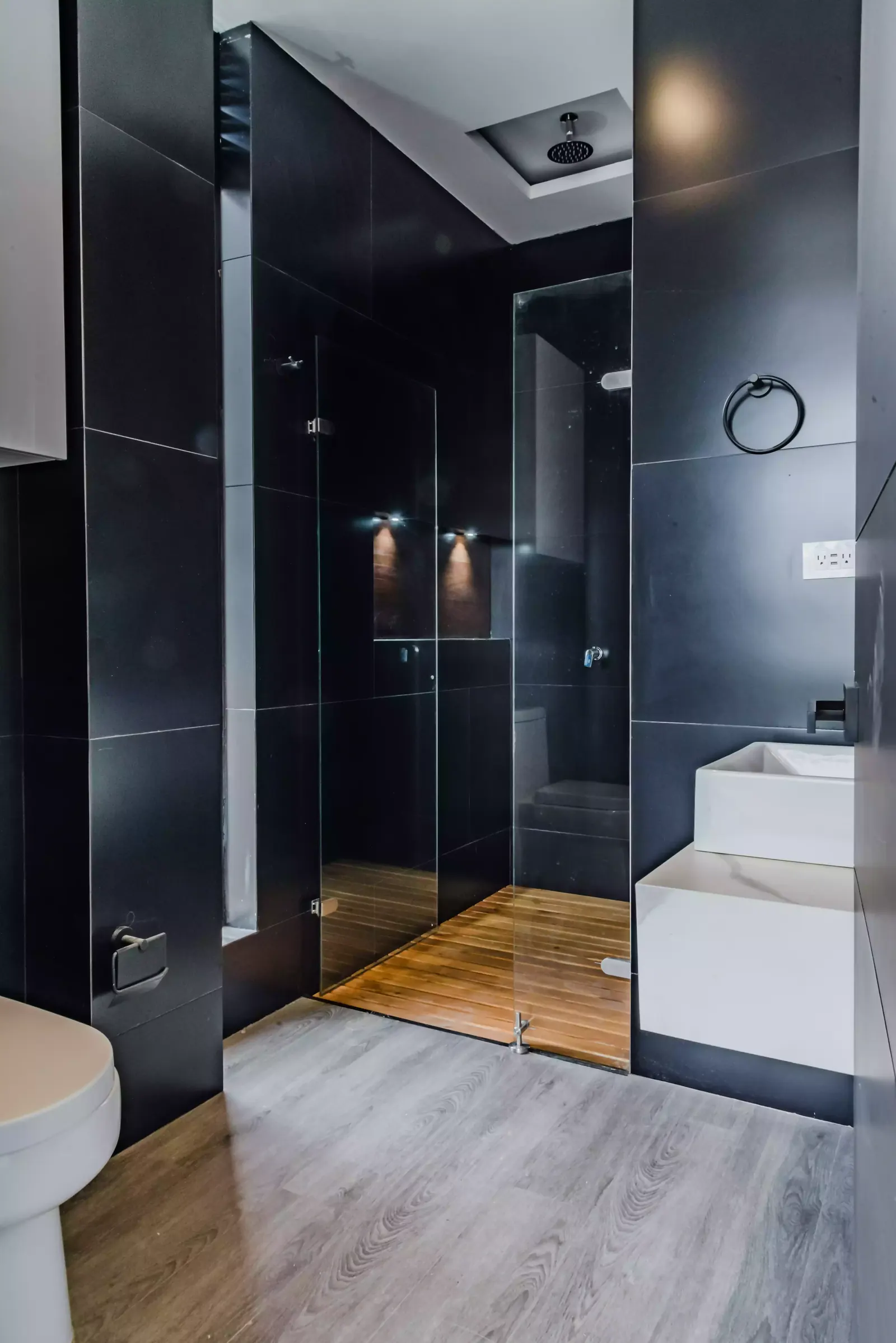 Baño principal en tonos oscuros con ducha en vidrio