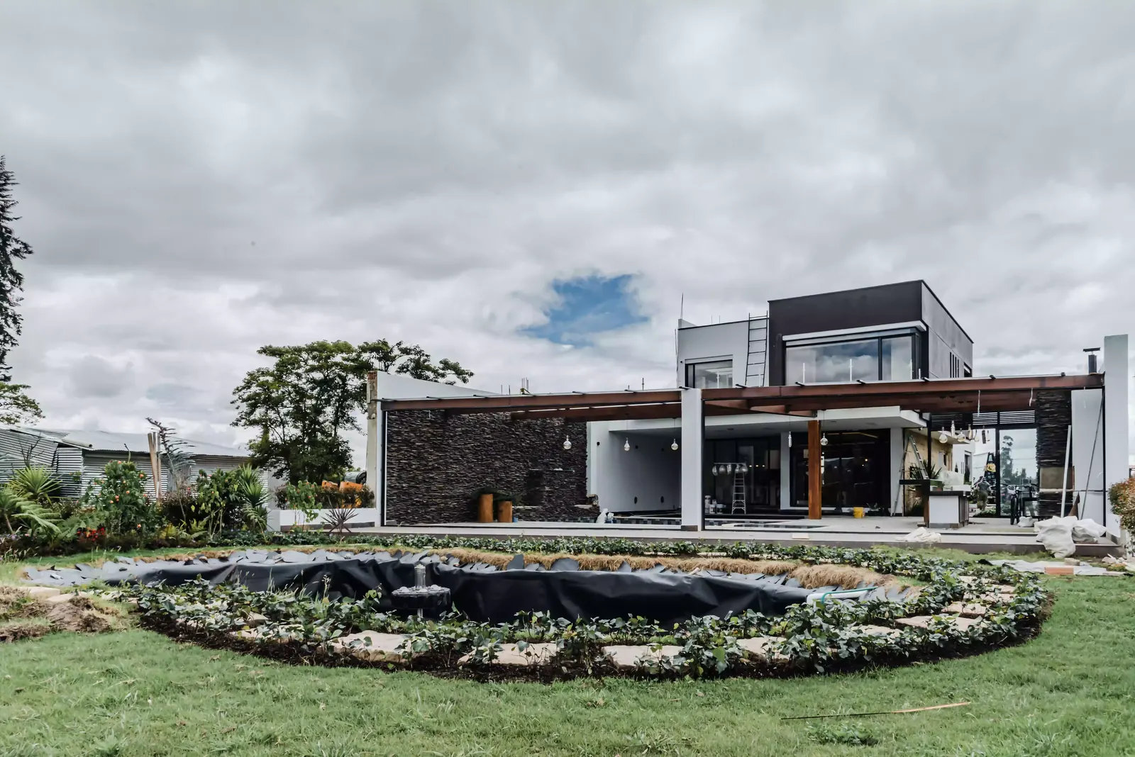 Fachada en piedra de la casa de dos pisos construida por Smartinn, con jardín