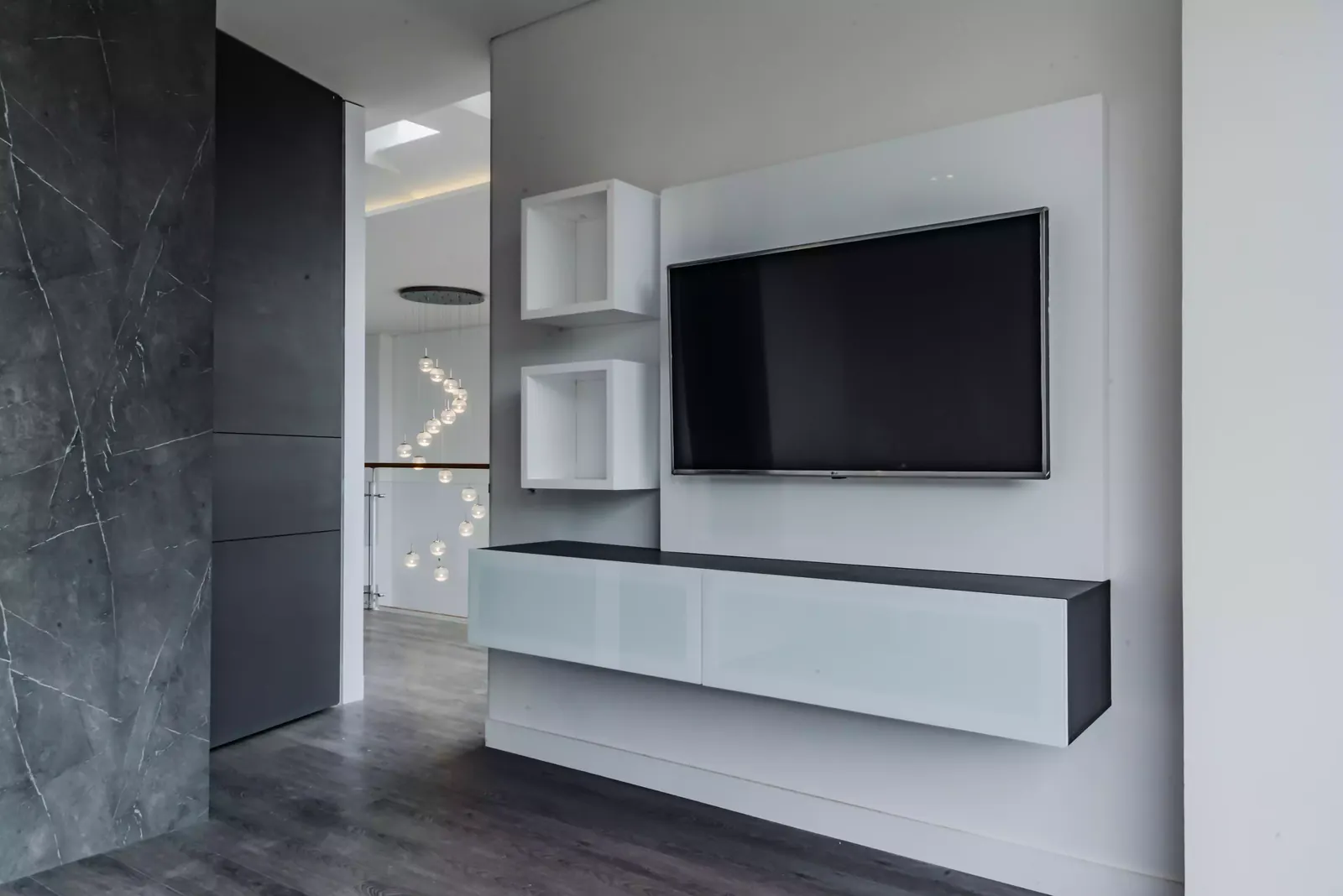 Mueble de televisión a medida con nichos abiertos junto a un muro de piedra