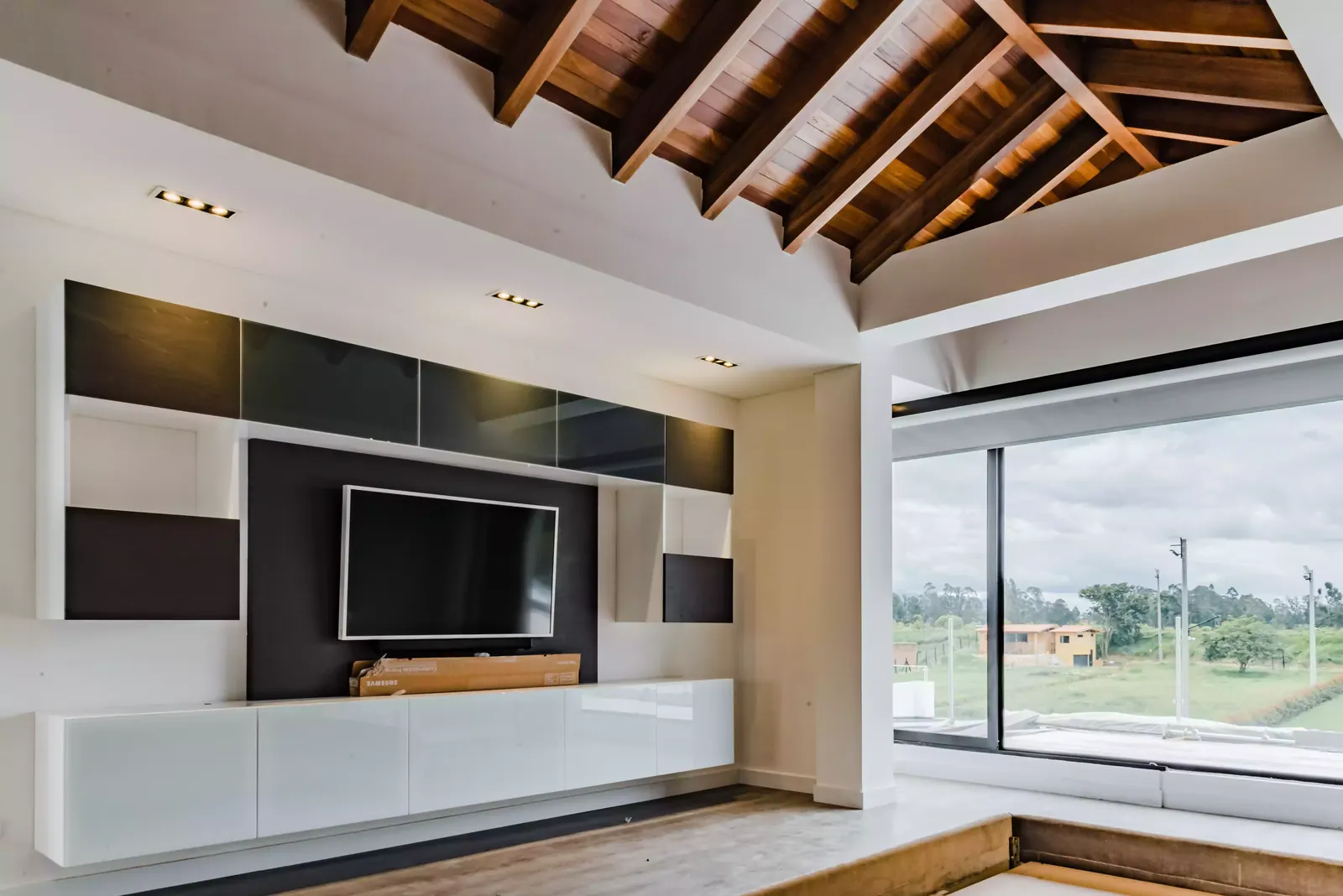 Sala con mueble de televisión flotante a medida y techo en madera