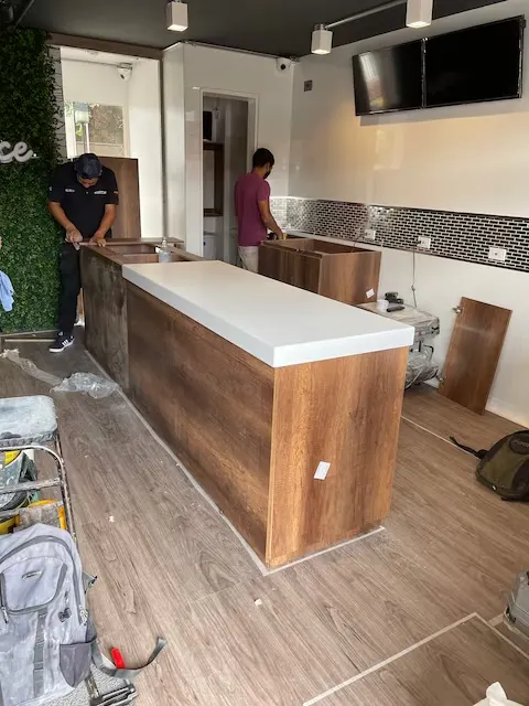 Integrantes de Smartinn instalando una barra de madera con tope blanco en un local comercial