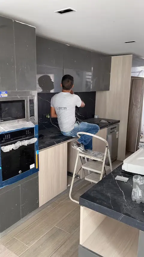 Instalación de una cocina a medida con mesón de mármol oscuro y muebles grises