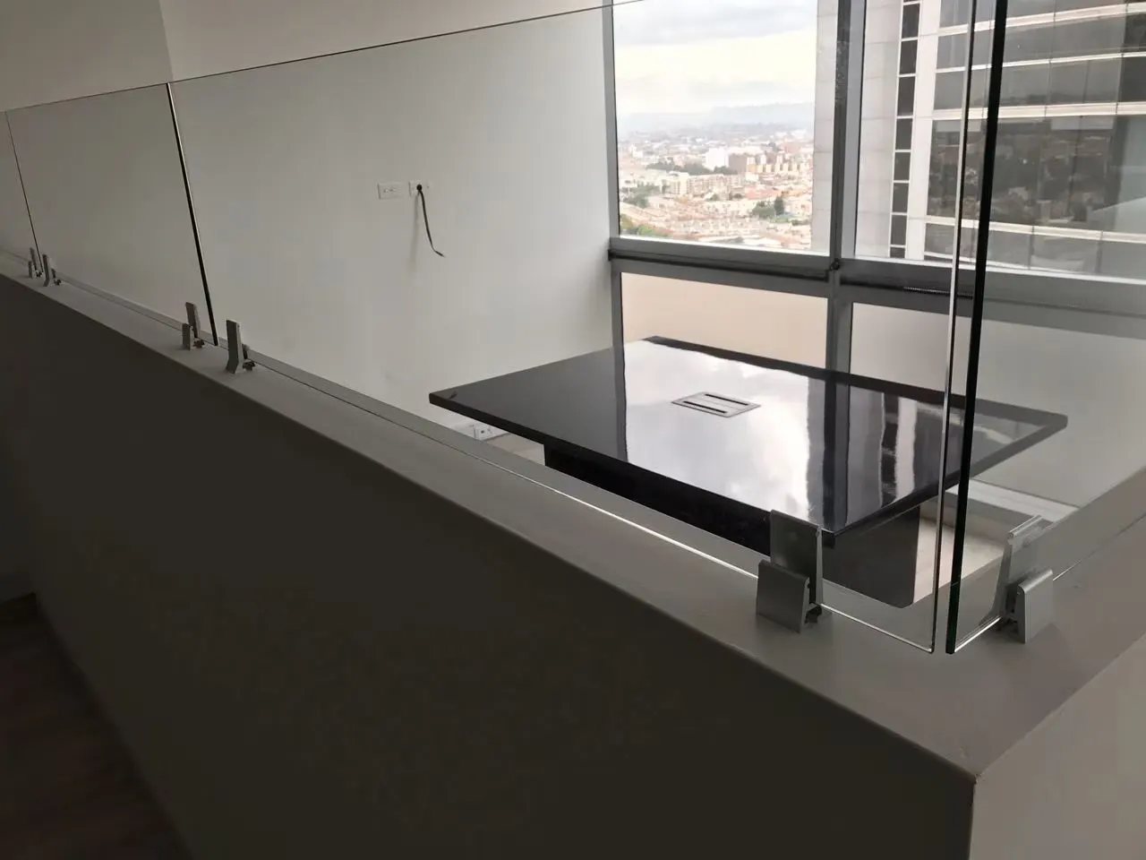 Mesa negra junto a un vidrio templado con vista a la ciudad en una oficina en altura