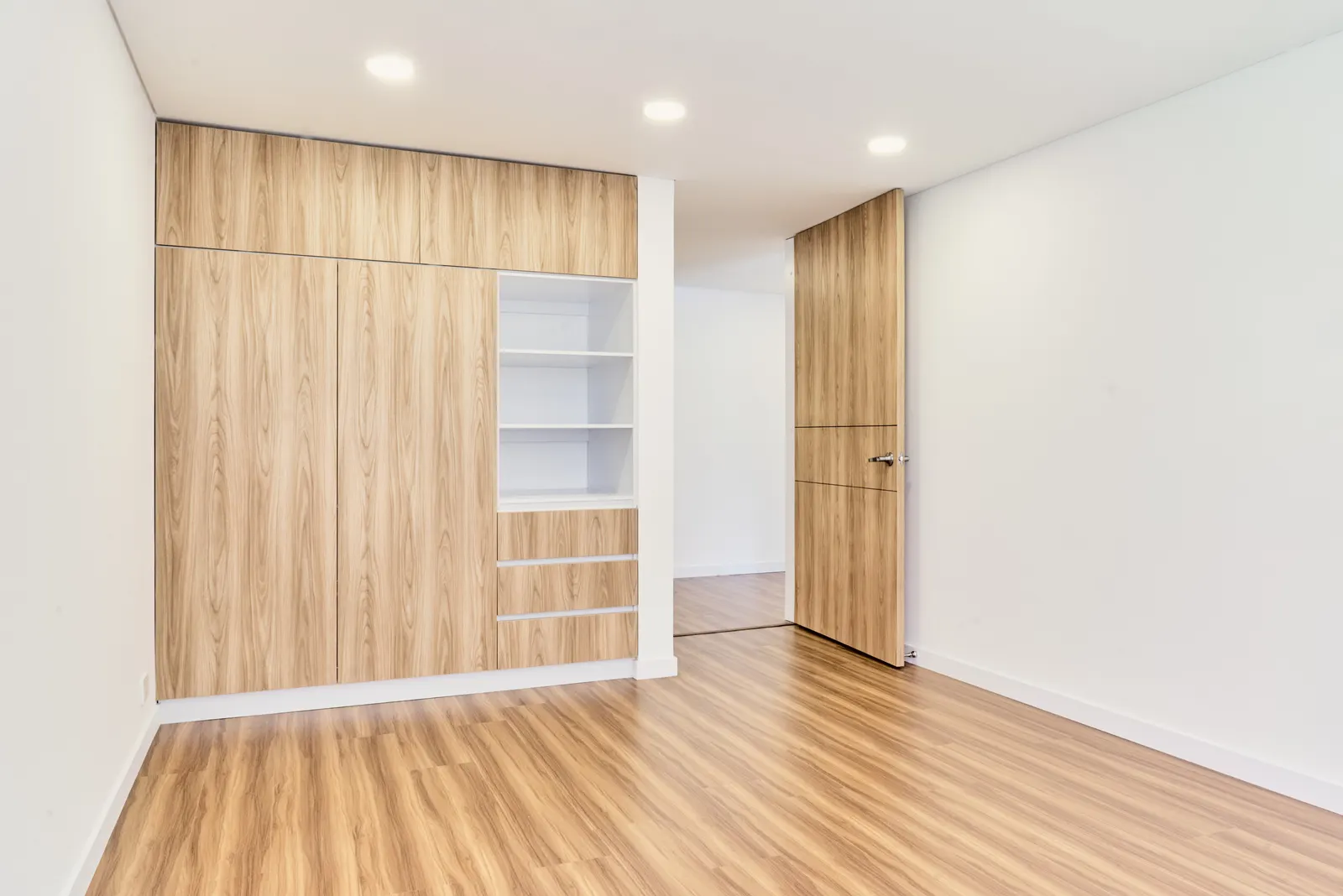 Closet empotrado en madera de piso a techo con nichos abiertos y cajones en una alcoba
