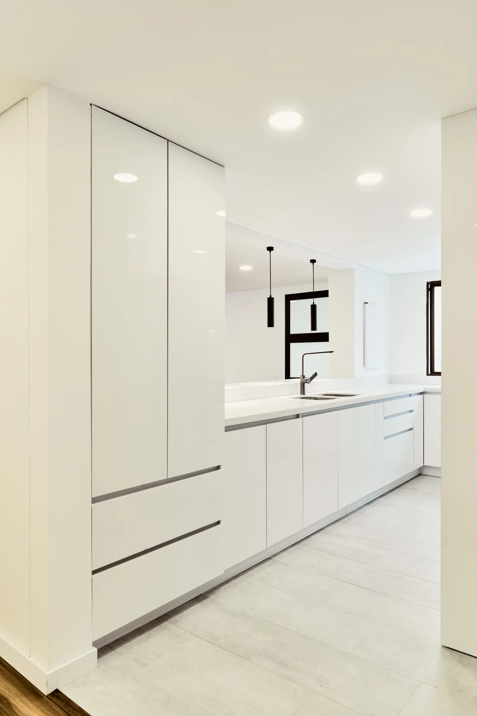 Cocina blanca con columnas de almacenamiento de piso a techo y mesón con cajones