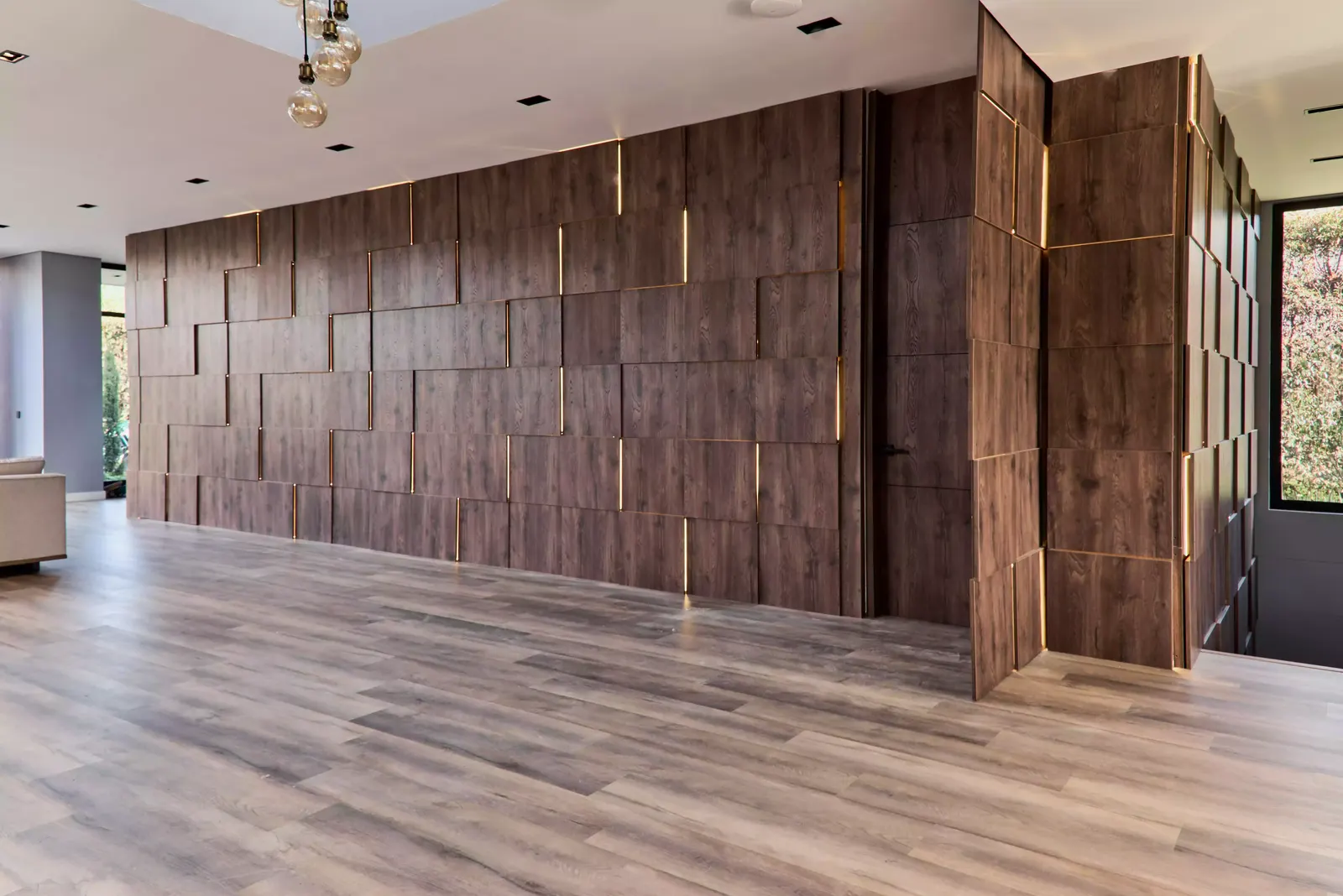 Muro largo de paneles de madera con juntas iluminadas en una casa
