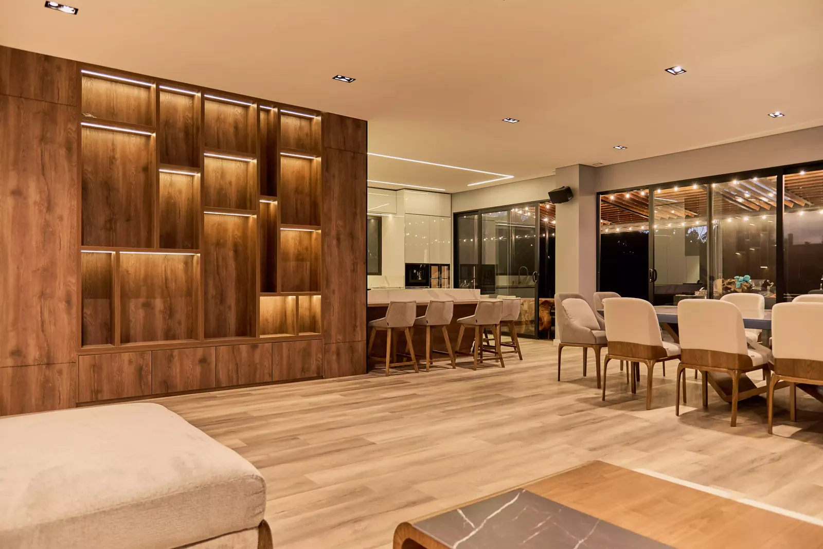 Biblioteca de madera con nichos iluminados, mobiliario a medida en la sala de una casa en Chía
