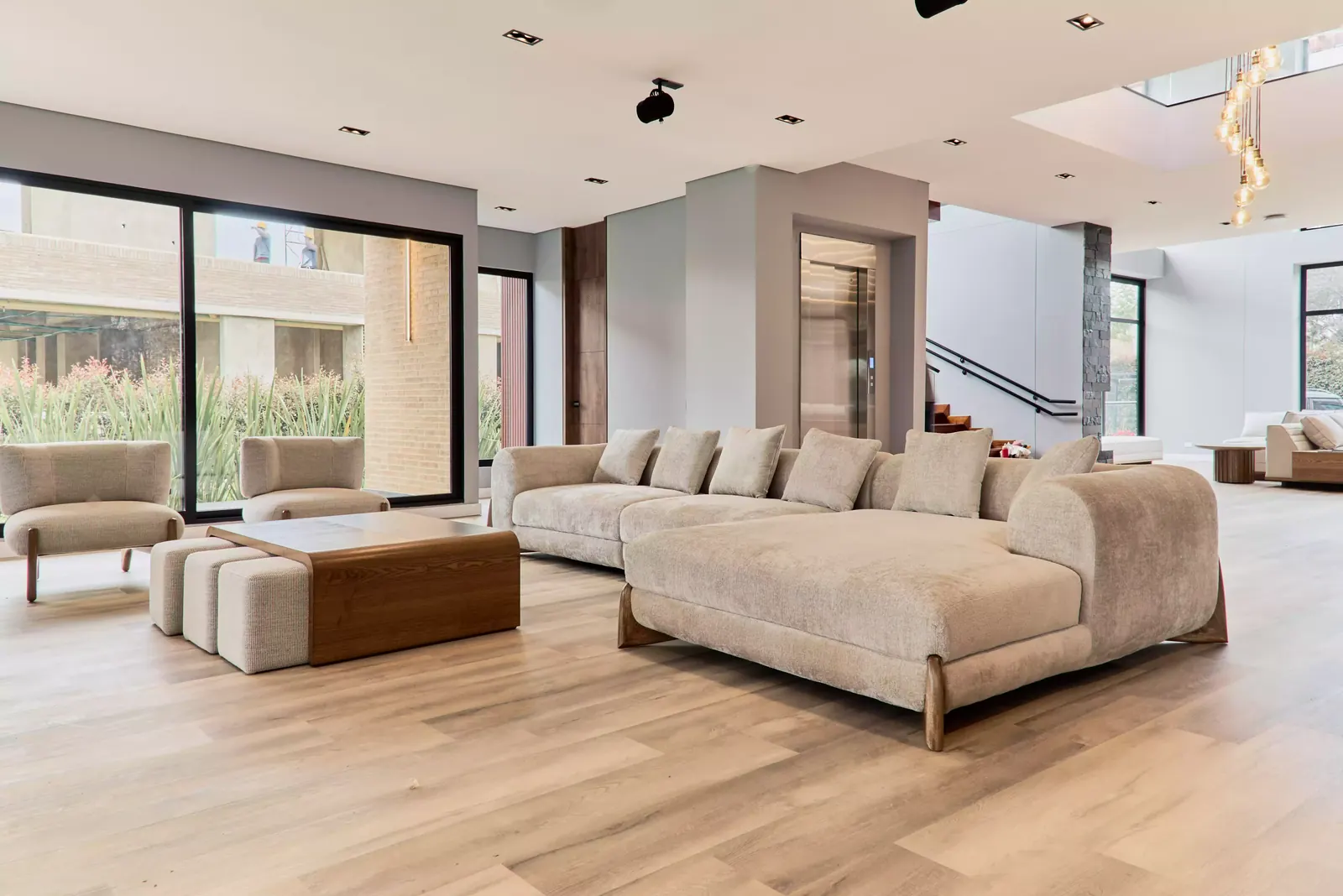 Sala principal de una casa en Chía con mobiliario en madera, sofá curvo y grandes ventanales