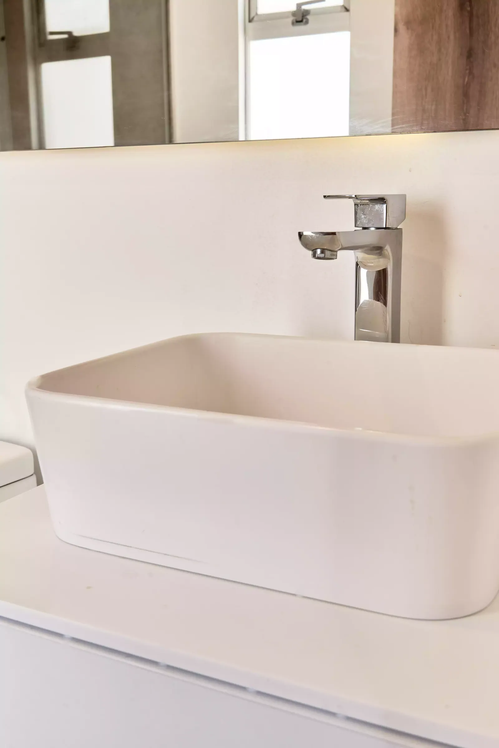 Lavamanos rectangular blanco sobre encimera con grifería cromada en un baño de apartamento