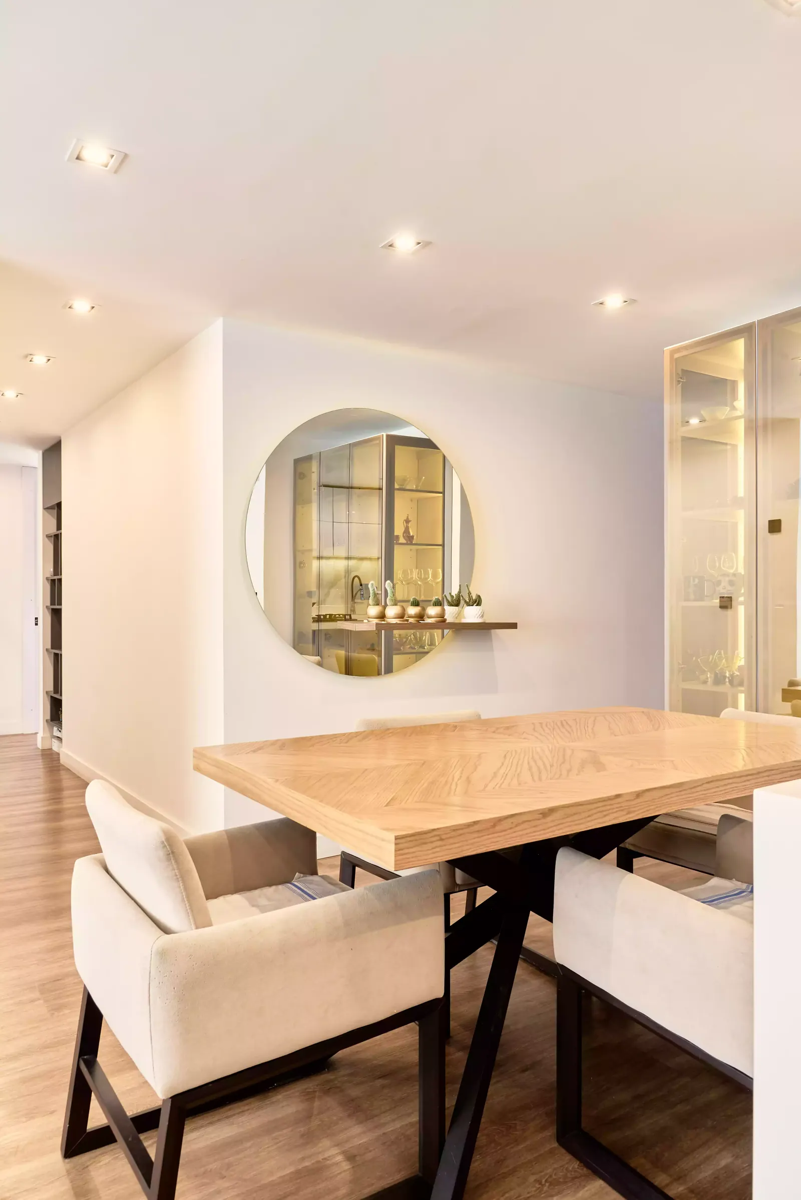 Comedor con mesa de madera y espejo circular en un apartamento con diseño de interiores de Smartinn