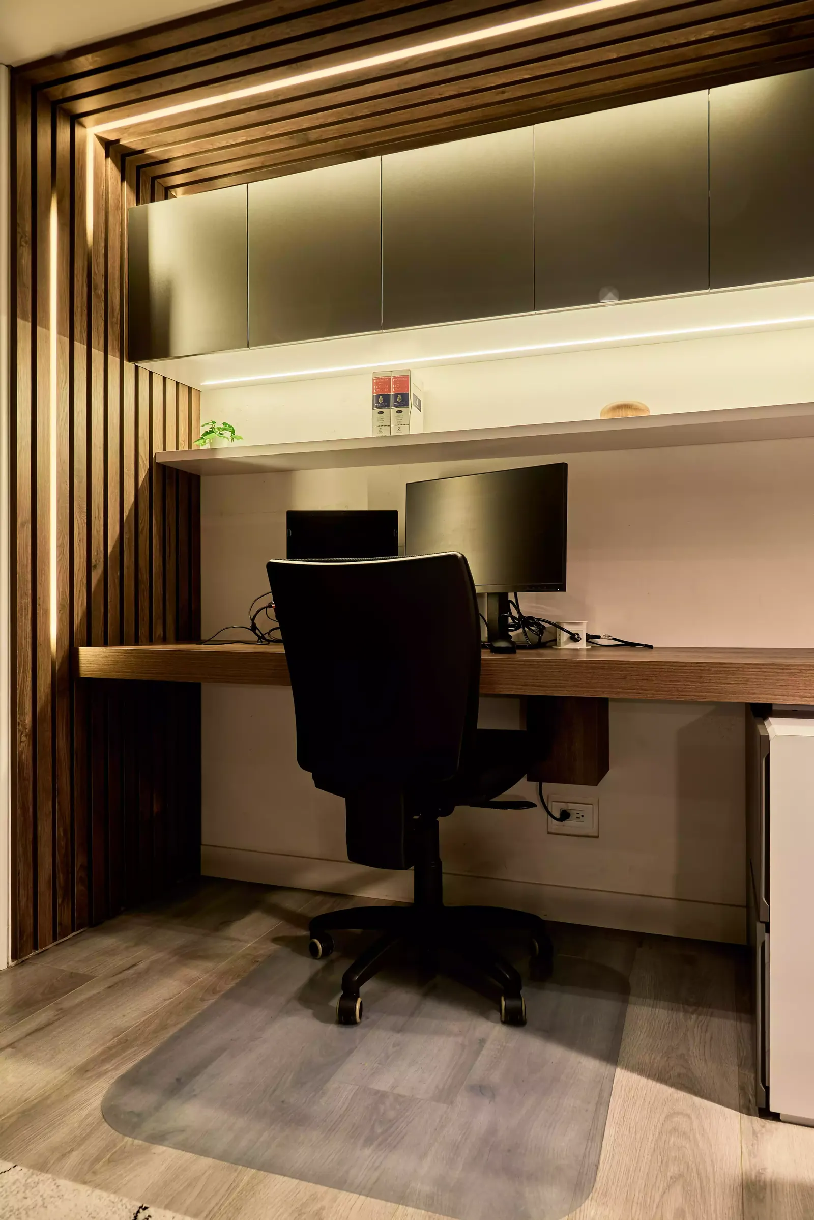 Estudio con listones de madera oscura e iluminación lineal integrada al mobiliario