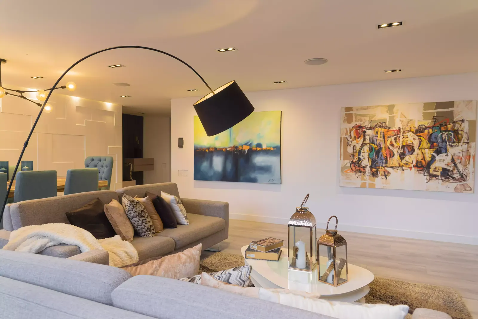 Sala y comedor de un apartamento con lámpara de arco, cuadros y parlantes empotrados en el cielo raso