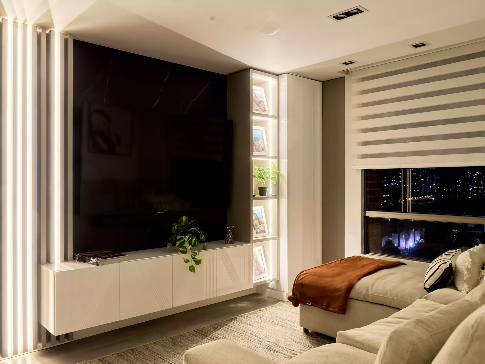 Mueble de televisión con repisas iluminadas en un apartamento con remodelación completa
