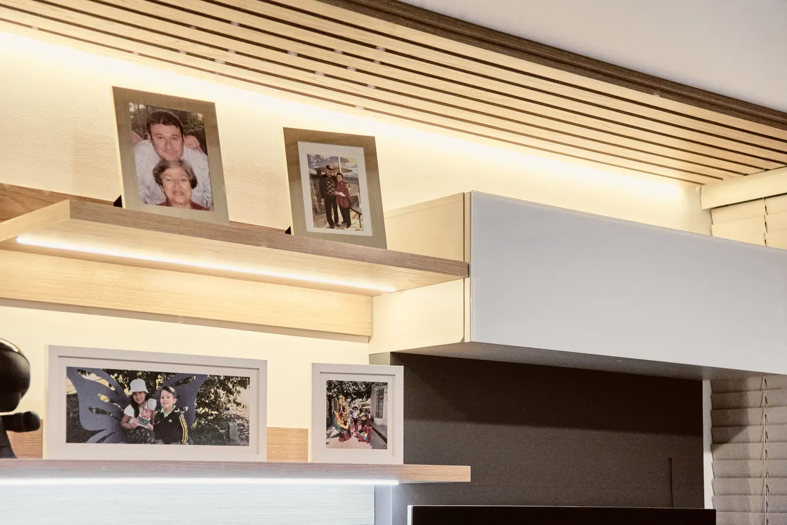 Repisas de madera con fotografías familiares y luz LED bajo el mueble superior
